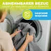A person is putting a gray blanket into a washing machine. Produktbild-Vorschau