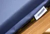 A close-up of a blue cushion with a label attached, resting on a wooden surface. Produktbild-Vorschau
