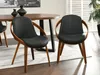 Two black dining chairs with wooden frames are placed around a wooden dining table in a well-lit room. Voir les images du produit