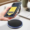 A hand holding a smartphone with a wireless charging receiver attached, hovering over a wireless charging pad on a desk. Náhled obrázku produktu