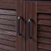 A close-up view of two black handles on a dark brown wooden cabinet with louvered doors. Náhľad obrázku produktu