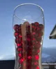 Rote transparente 16 mm Glasmurmeln im Glas vor hellem Himmel mit leuchtender Lichtwirkung. Produktbild-Vorschau