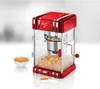 A retro-style red and chrome popcorn machine is shown in a studio setting, with popcorn kernels in a bowl and in a measuring scoop. Náhled obrázku produktu