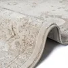 A close-up view of a beige rug with a vintage pattern, showing the texture and the rolled edge. Produktbild-Vorschau