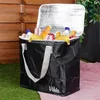 A black cooler bag filled with drinks and fruit, placed on a pink blanket on grass, with a wooden fence in the background. Anteprima dell’immagine prodotto