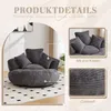 A dark gray bean bag chair with multiple cushions, shown in a room setting with a patterned rug and a hint of a window and plant. Produktbild-Vorschau