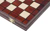 A close-up view of a wooden chessboard with a brass hinge visible on the side. Voir les images du produit