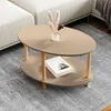 A modern oval coffee table with a two-tiered design, placed on a textured rug next to a sofa. Voir les images du produit
