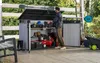 A man is organizing tools and equipment inside a large outdoor storage shed. Anteprima dell’immagine prodotto