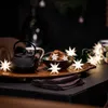 A festive table setting with a teapot, cookies, and star-shaped lights. Produktbild-Vorschau