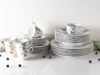 A set of porcelain dishes with a cherry and leaf motif, arranged on a white surface with a few blueberries scattered around. Produktbild-Vorschau