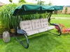 A garden swing with cushions is set up on a lawn, surrounded by plants and flowers. Náhľad obrázku produktu