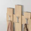 A close-up shot of a wooden coat rack with metal hooks, featuring a pink scarf and a brown bag hanging on it. Náhled obrázku produktu