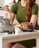 A person is eating food from a glass dish next to a Ninja CRISPi air fryer. Anteprima dell’immagine prodotto