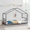 A child's bed with a house-shaped frame, decorated with a string of colorful figures and a framed picture on the wall.