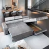 A modern living room scene featuring a gray sectional sofa that can be converted into a bed, with a dining area and staircase in the background. Podgląd zdjęcia produktu