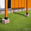 Two wooden posts are anchored to the ground with concrete blocks and metal brackets, next to an orange-sided building. Anteprima dell’immagine prodotto
