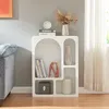 A white shelving unit with decorative items is placed next to a sofa and a window with sheer curtains. Anteprima dell’immagine prodotto