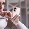 A woman is holding and looking at a smartphone with a rose-colored case. Produktbild-Vorschau