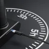 A close-up of a black charging cable plugged into a black device, with a circular dial in the background showing time markers. Podgląd zdjęcia produktu