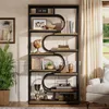 A tall, multi-shelf industrial-style bookshelf filled with decorative items and books, placed in a well-lit room with curtains and a chair visible. Podgląd zdjęcia produktu