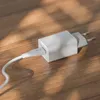 A white USB charger and cable are placed on a wooden surface. Produktbild-Vorschau
