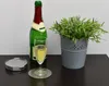 A champagne bottle, a glass of champagne, a coaster set, and a potted plant are arranged on a dark brown surface against a white background. Produktbild-Vorschau