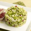 A close-up of a dessert ring filled with diced avocado, radish, and chives, served with slices of seared tuna on a white plate. Produktbild-Vorschau