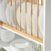 A close-up view of a white plate rack filled with white plates, with a stack of white bowls on the shelf below. Produktbild-Vorschau