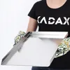 A person wearing oven mitts holds a rectangular baking sheet. Anteprima dell’immagine prodotto