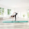 A woman is performing a yoga pose on an air track in a bright, airy room. Produktbild-Vorschau