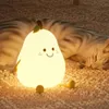 A cute pear-shaped night light is sitting on a carpet next to a sleeping cat. Produktbild-Vorschau