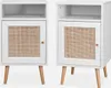 A pair of white bedside tables with rattan woven doors and wooden legs, presented against a white background. Produktbild-Vorschau