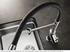 A close-up shot of a modern kitchen faucet with a flexible black hose, positioned over a stainless steel sink. Produktbild-Vorschau