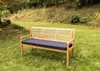 A wooden bench with a black cushion sits on a grassy lawn in a garden setting. Voir les images du produit