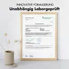 A framed certificate is displayed on a white surface with a small decorative plant in a vase in the foreground. Produktbild-Vorschau