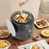 A person is using a ladle to serve soup from a large black electric soup kettle on a wooden table. Other dishes of food are arranged around the kettle. Náhled obrázku produktu
