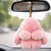 Rosa flauschiger Hasen-Schlüsselanhänger mit goldener Beschläge, am Rückspiegel eines Autos hängend Anteprima dell’immagine prodotto