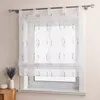 A white sheer curtain with a brown embroidered pattern is hung on a window. Produktbild-Vorschau