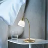 A bedside table with a lamp and a glass of water next to a bed. Produktbild-Vorschau