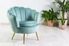 A mint green velvet armchair with gold legs is placed on a light wooden floor next to several potted plants. Produktbild-Vorschau