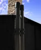 Close-up of two black poles with a black fabric screen attached, against a blue sky with clouds and a brick chimney in the background. Produktbild-Vorschau