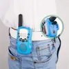 A blue walkie-talkie is clipped to a person's belt loop. Produktbild-Vorschau