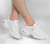 A pair of white Skechers D-Lites sneakers with rose gold accents, worn by a person wearing beige leggings. Voir les images du produit
