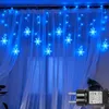 Blue snowflake string lights hanging in front of sheer white curtains. Náhled obrázku produktu