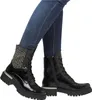 A pair of black lace-up boots worn by a person. Voir les images du produit