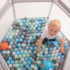 A young child is playing in a hexagonal ball pit filled with colorful balls. Voir les images du produit