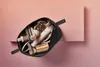 A black cosmetic bag filled with hair styling tools, placed on a pink shelf against a pink background. Voir les images du produit