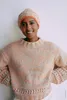 A woman wearing a knitted sweater and hat. Produktbild-Vorschau