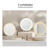 Three illuminated makeup mirrors are displayed on a shelf with decorative items. Voir les images du produit